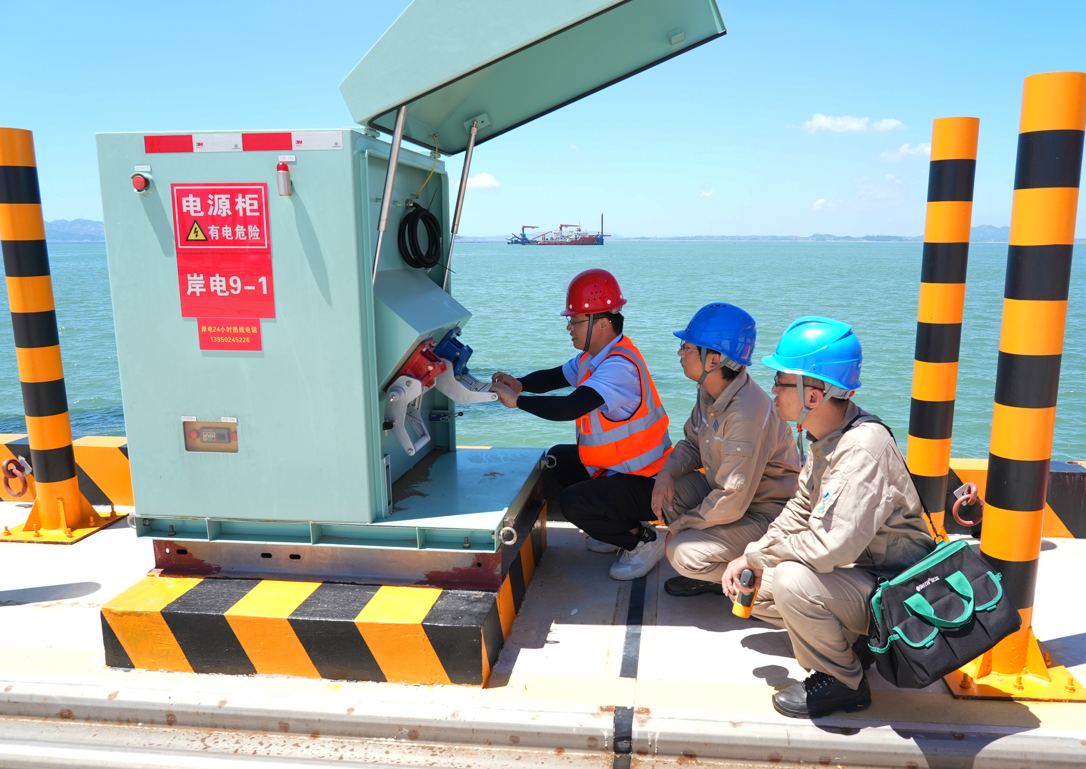 7月3日福建福州供电公司员工林森和钱骅冒着40℃的高温对福建省东北地区首个零排放全电动码头——融港码头的岸电设备进行巡检（陈德钧）.jpg